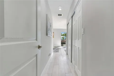 a view of a hallway with wooden floor and a bathroom
