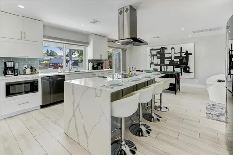 a kitchen with stainless steel appliances a stove a sink a oven a dining table and chairs