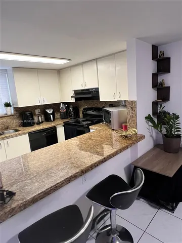 a kitchen with granite countertop a stove a sink and a white cabinets