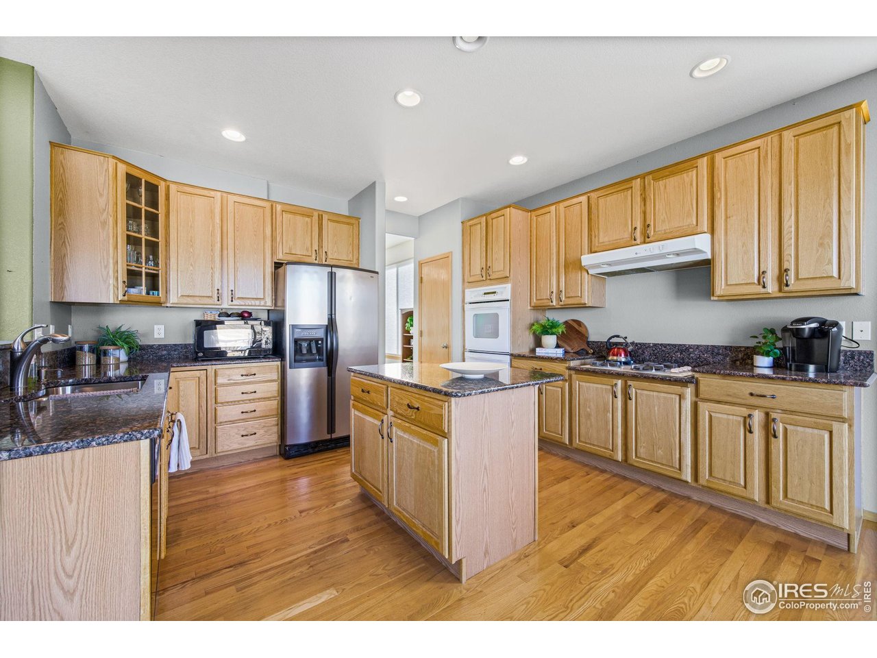 7133 Ranger Drive Fort Collins, CO 80526 - Photo 14 of 33 a kitchen with stainless steel appliances granite countertop a refrigerator a sink dishwasher a stove with wooden cabinets and floor
