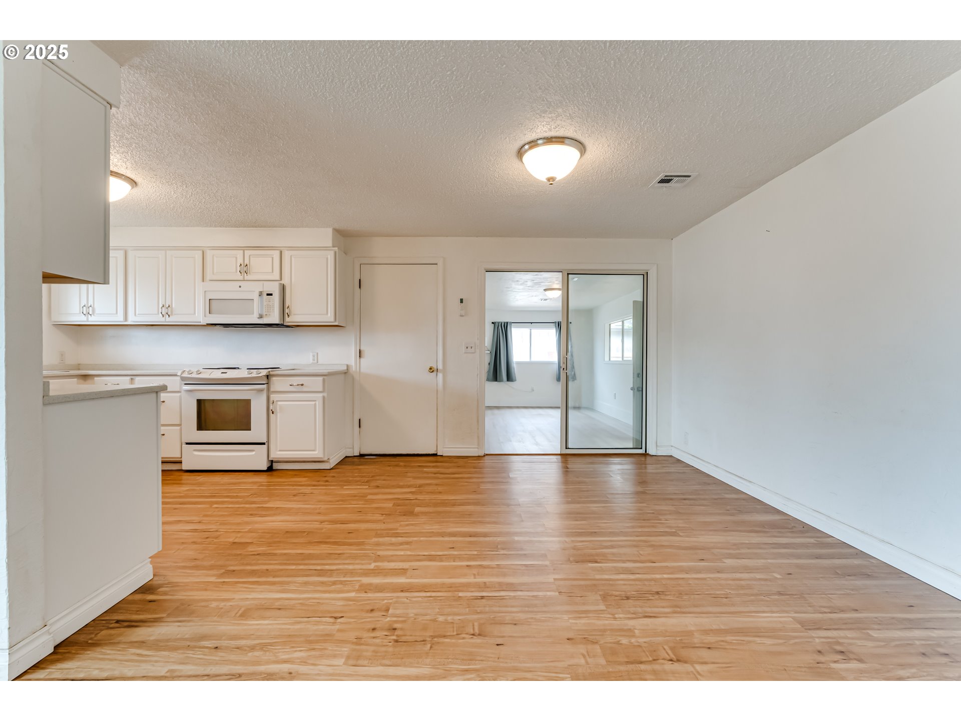 1753 10th Street Springfield, OR 97477 - Photo 8 of 35 a view of an empty room and kitchen with wooden floor