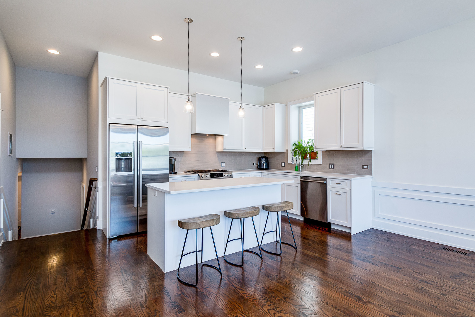 2453 West Irving Park Road, Unit 3W Chicago, IL 60618 - Photo 5 of 15 a kitchen with kitchen island white cabinets stainless steel appliances and wooden floor