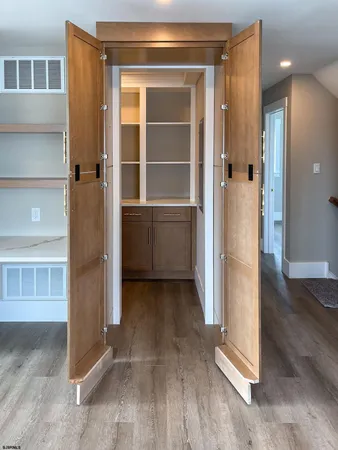 a view of a hallway with wooden floor and a bathroom