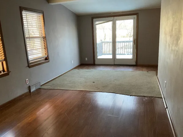 an empty room with wooden floor and windows with curtains view
