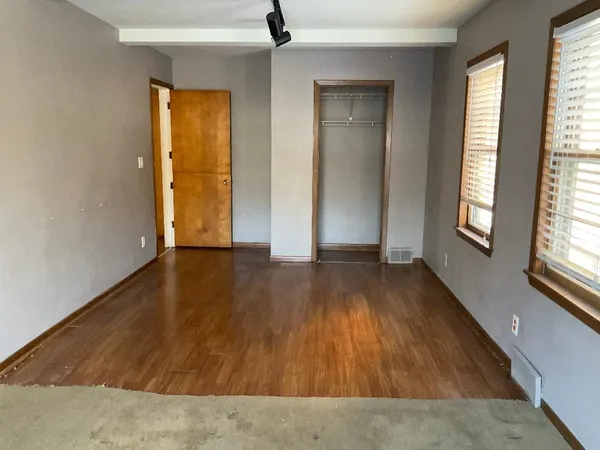 an empty room with wooden floor and windows with curtains view