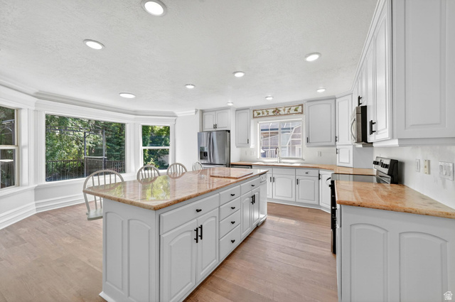 883 East 700 South Springville, UT 84663 - Photo 9 of 59 Kitchen featuring a large bay window, recessed lighting, wood-finish flooring, white cabinetry, and a central island with a stone-finish countertop