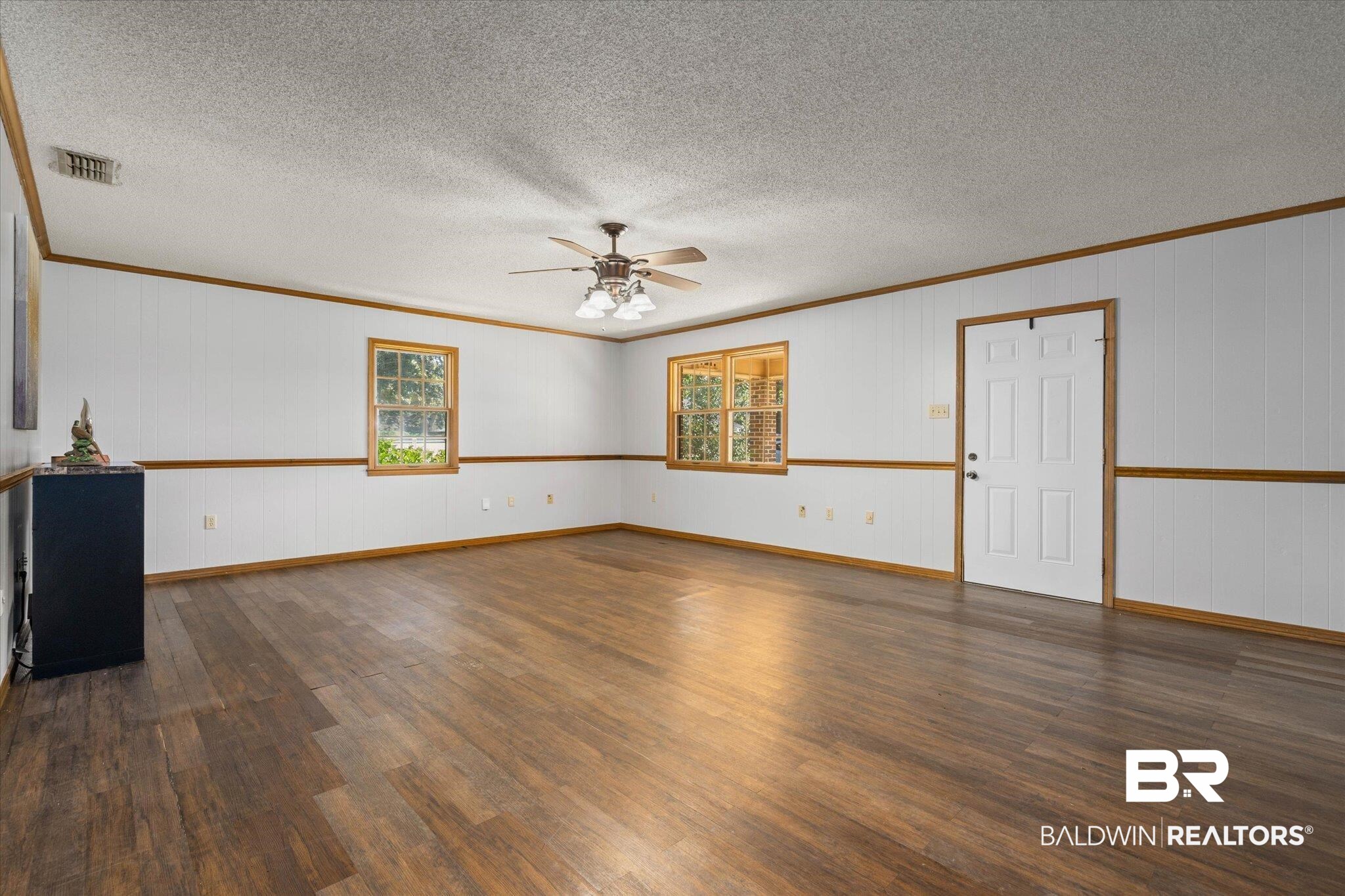 5503 Darring Street Satsuma, AL 36572 - Photo 3 of 31 Unfurnished room featuring a ceiling fan, ornamental molding, wood finished floors, a textured ceiling, and wooden walls