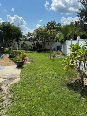 a backyard of a house with table and chairs plants and large tree