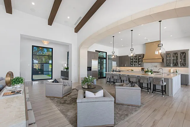 a kitchen with stainless steel appliances a stove a sink a oven a kitchen island with chairs and wooden floor