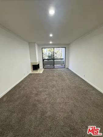 an empty room with windows and fireplace
