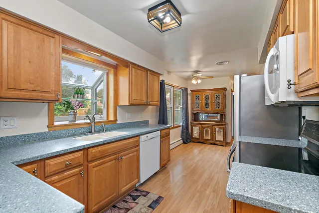 a kitchen with stainless steel appliances granite countertop a sink dishwasher stove and refrigerator with wooden floor