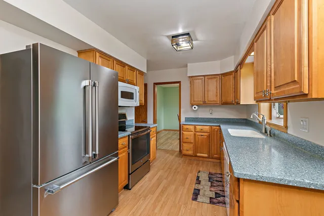 a kitchen with stainless steel appliances granite countertop a refrigerator a stove and a sink with cabinets