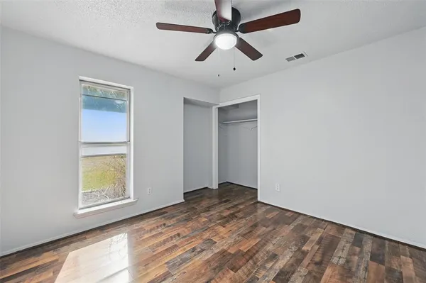 an empty room with a window and a ceiling fan