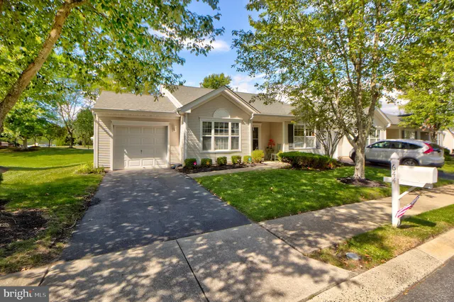 a front view of a house with a garden and trees