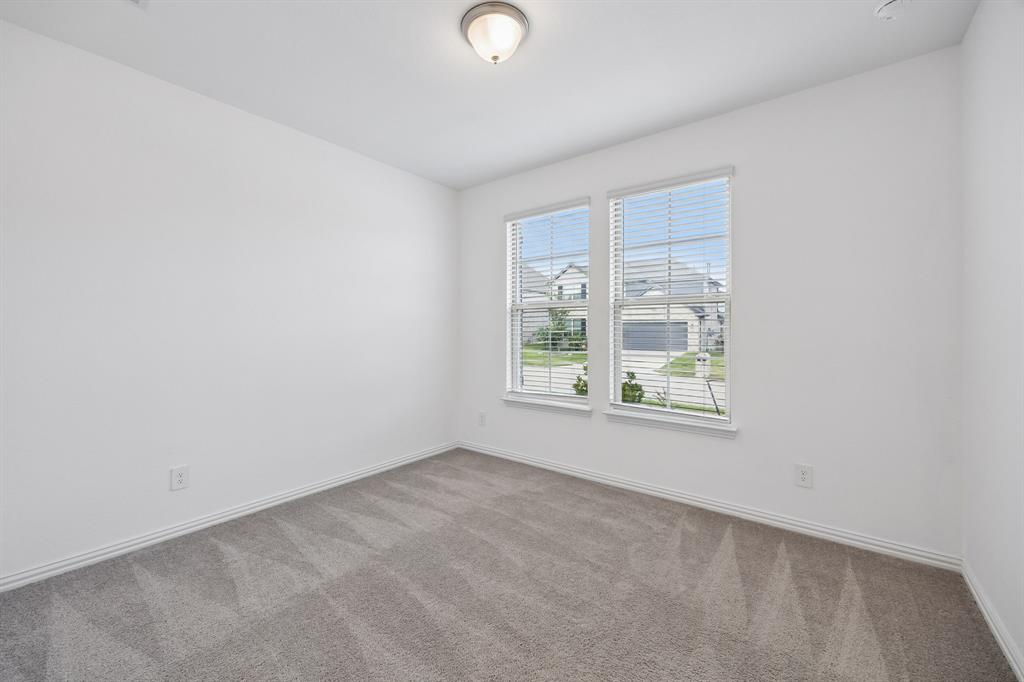 1303 Wheelwright Drive Forney, TX 75126 - Photo 25 of 39 1st floor guest bedroom with white walls defining a bright room with dual windows, gray patterned carpet, white trim, and a flush-mount ceiling light