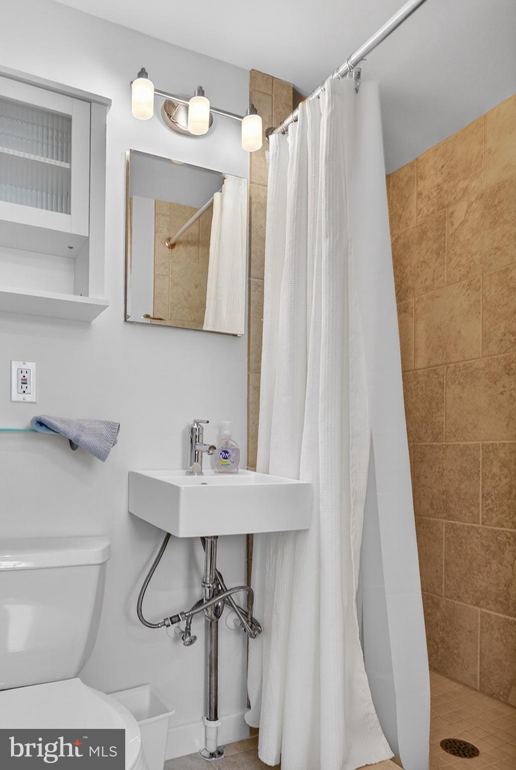 11 Newbold Square, Unit 11 Rehoboth Beach, DE 19971 - Photo 11 of 21 a bathroom with a sink a toilet and shower curtain