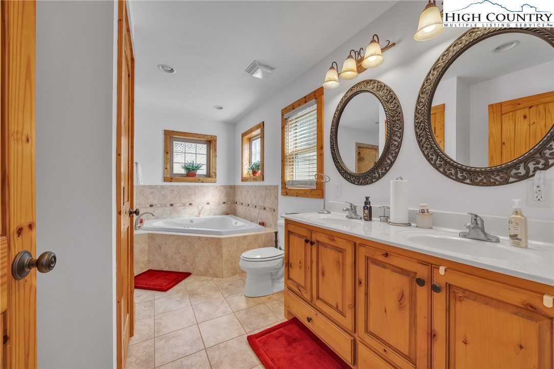 1118 Lucy Bell Road Crumpler, NC 28617 - Photo 14 of 39 a bathroom with a granite countertop toilet a sink and a mirror
