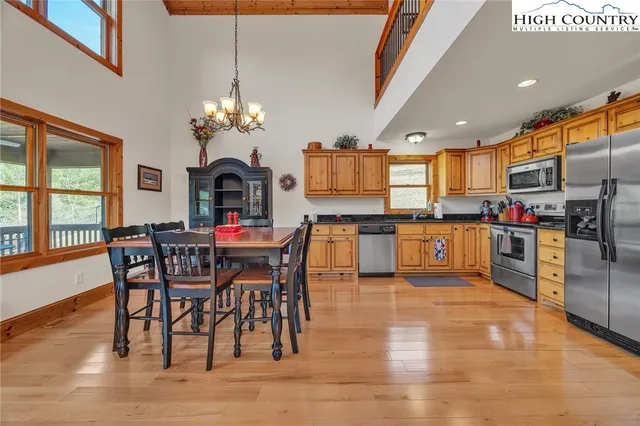 a kitchen with stainless steel appliances granite countertop a dining table chairs refrigerator and microwave