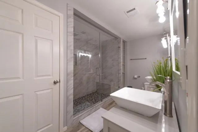 a bathroom with a granite countertop sink a toilet and shower