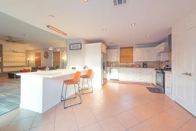 a room with stainless steel appliances kitchen island granite countertop a sink and cabinets