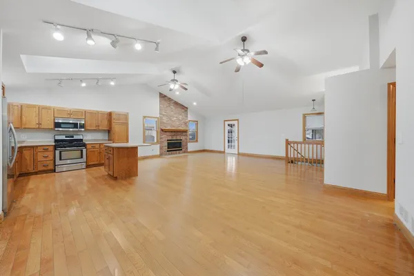 a view of an empty room with kitchen and a window