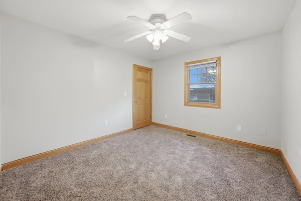 an empty room with a chandelier fan and windows