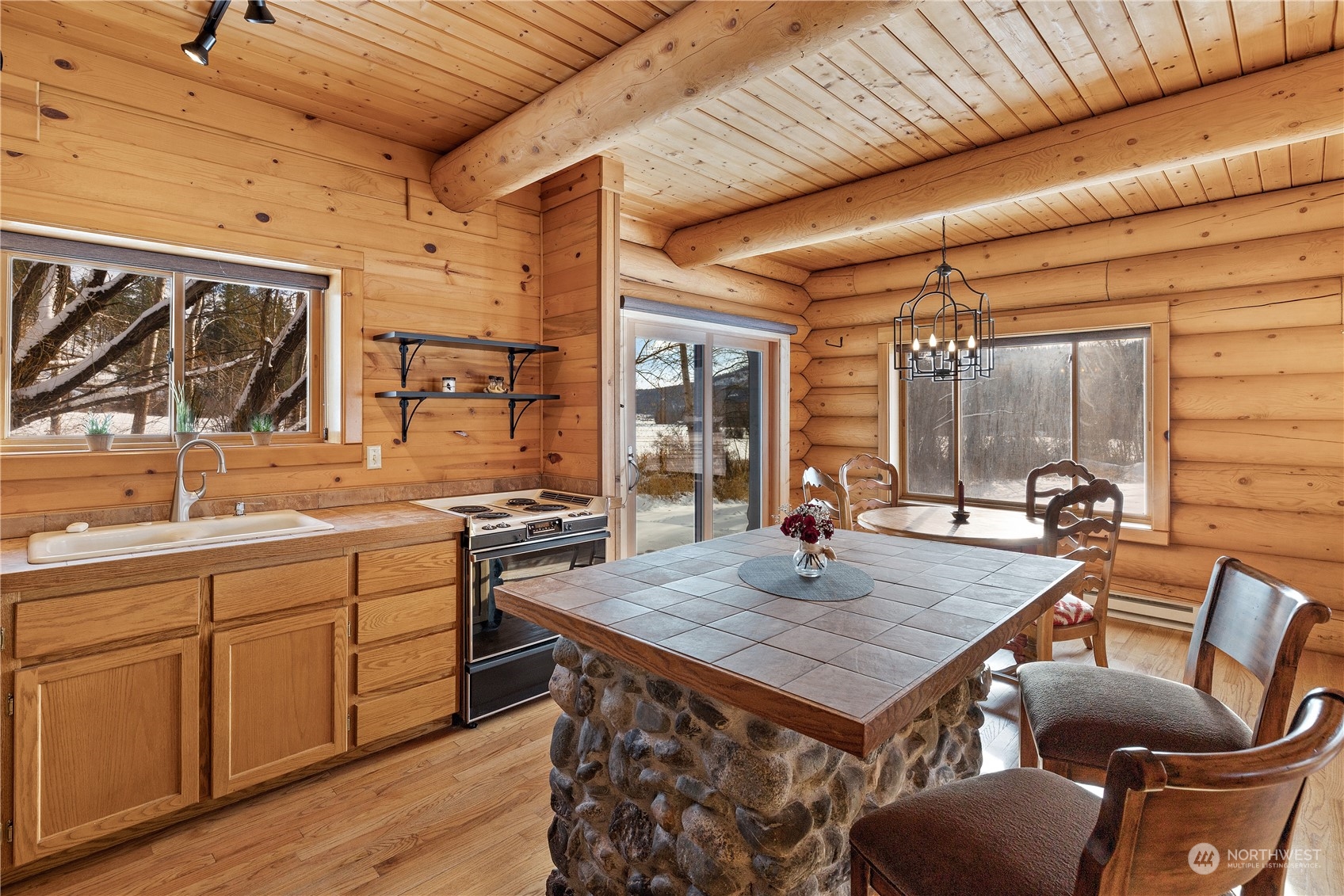 3435 Teanaway Road Cle Elum, WA 98922 - Photo 18 of 33 a kitchen with a stove a sink dishwasher and a dining table with wooden floor