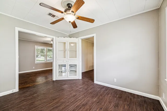 an empty room with wooden floor ceiling fan and windows