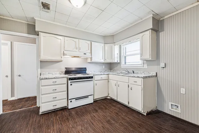 a kitchen with granite countertop white cabinets white appliances and wooden floors