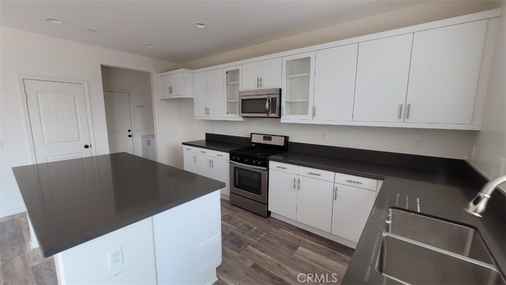 22056 Windham Way Saugus, CA 91350 - Photo 7 of 35 a kitchen with granite countertop white cabinets and black appliances