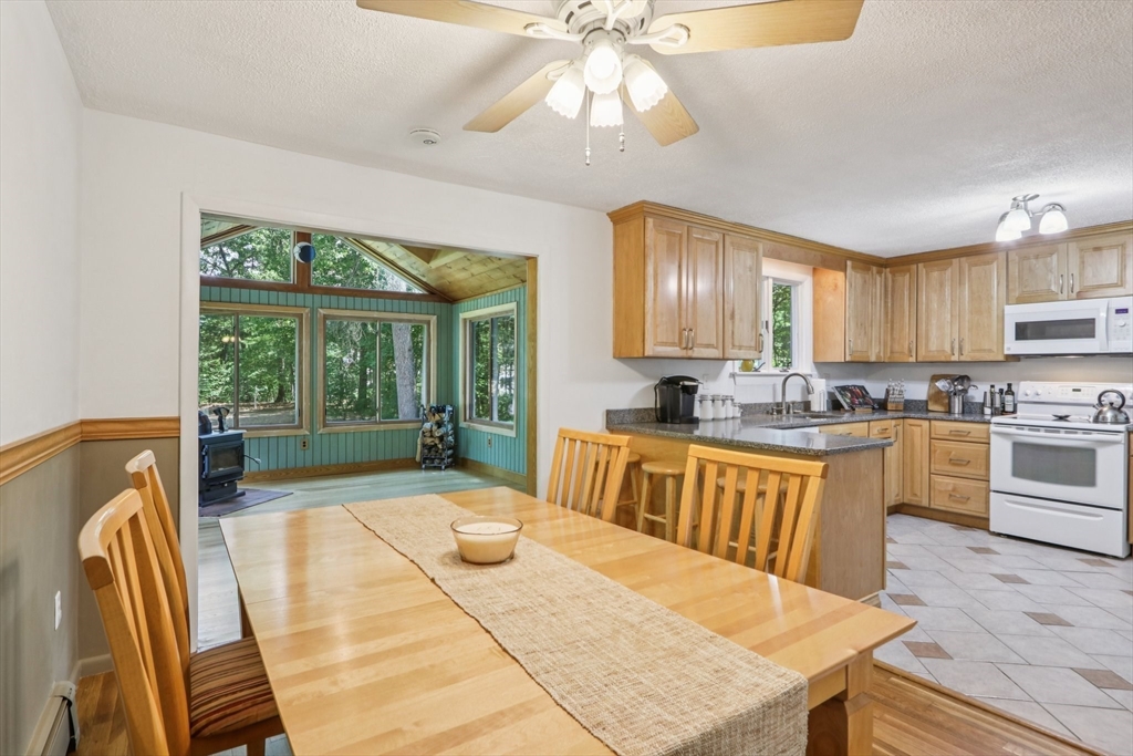 196 Hudson Road Stow, MA 01775 - Photo 8 of 31 a kitchen with stainless steel appliances granite countertop a stove a sink a dining table and chairs with wooden floor