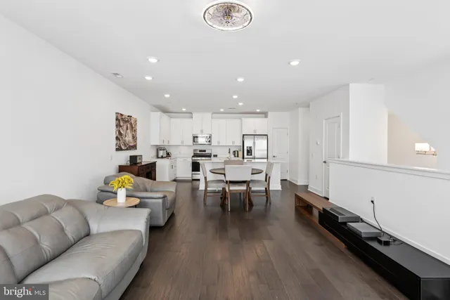 a living room with furniture kitchen view and a wooden floor