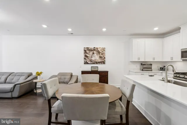 a living room with stainless steel appliances furniture a couch and a kitchen view