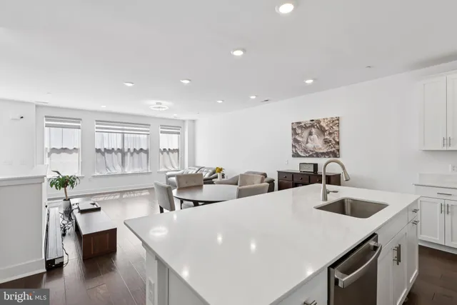 a living room with stainless steel appliances kitchen island granite countertop a sink and a refrigerator