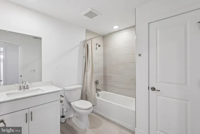 a bathroom with a bathtub shower sink vanity and toilet