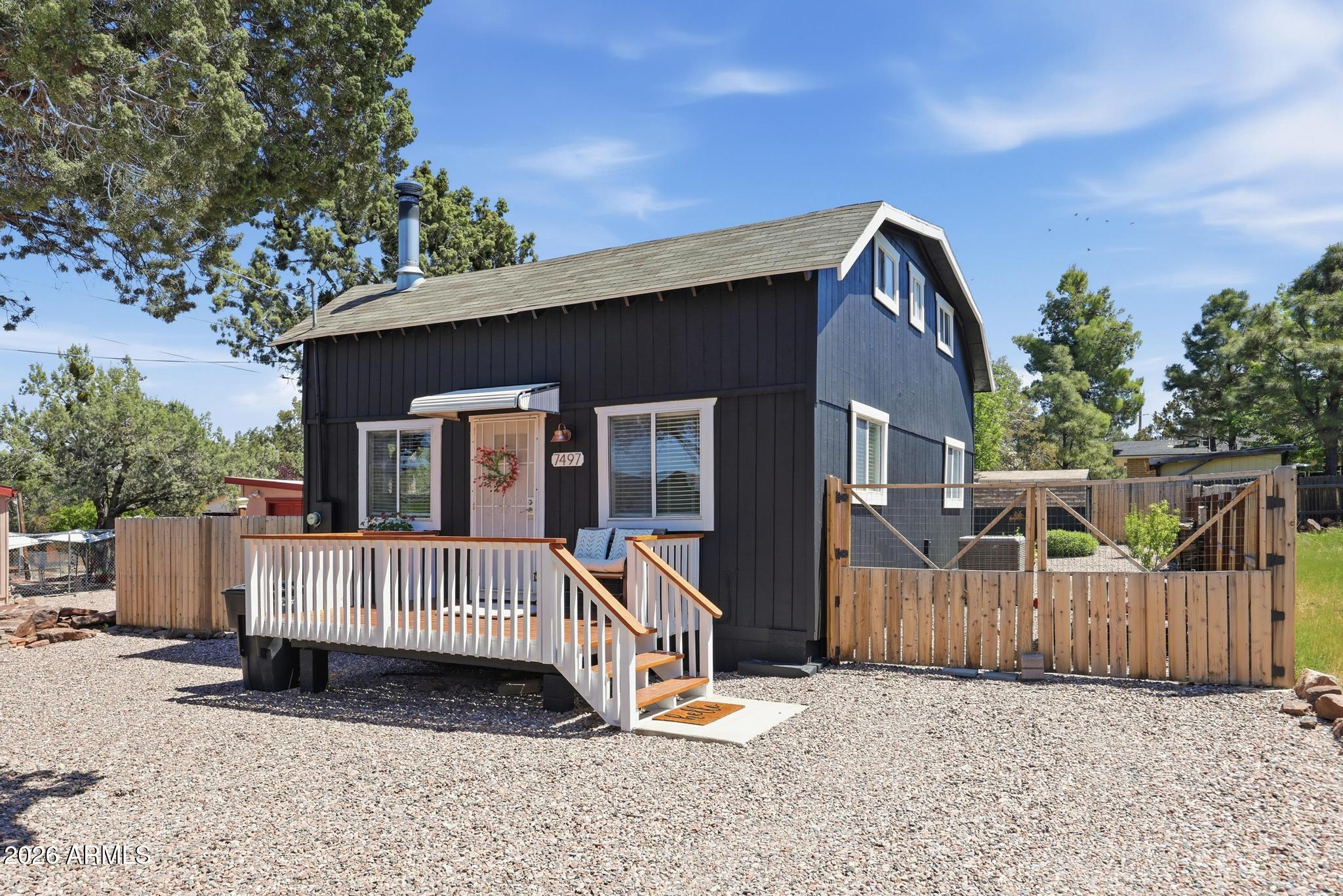 a view of a wooden house with a small yard and wooden fence