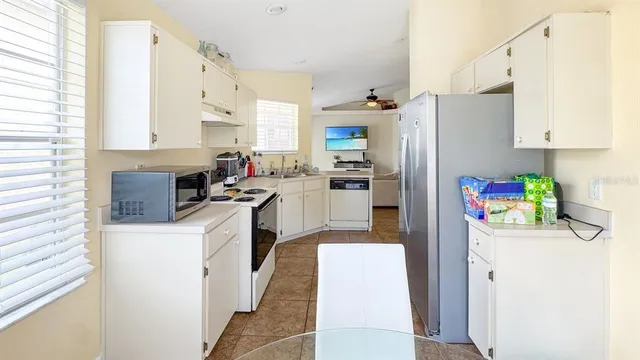 a kitchen with a refrigerator a stove a sink dishwasher and white cabinets with wooden floor
