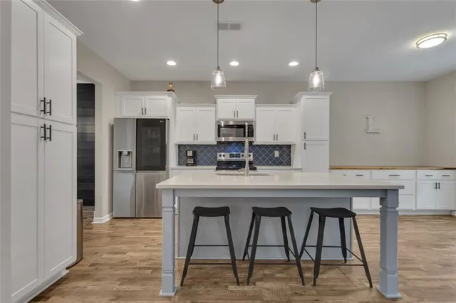 a kitchen with stainless steel appliances granite countertop a table chairs refrigerator and microwave