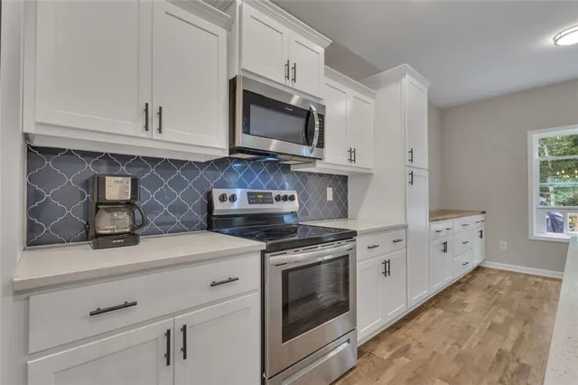 a kitchen with granite countertop white cabinets stainless steel appliances and sink