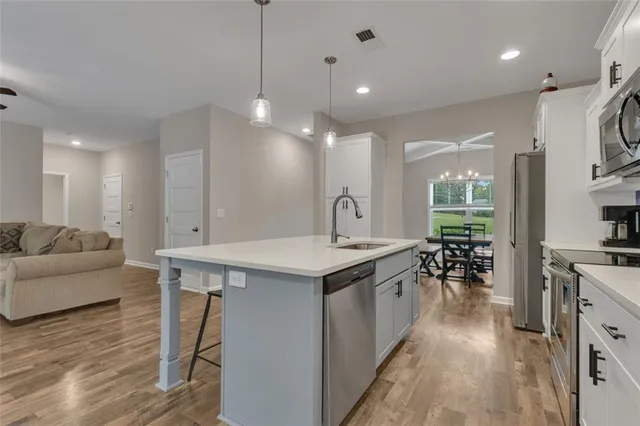 a kitchen with stainless steel appliances granite countertop a sink a stove and a wooden floors