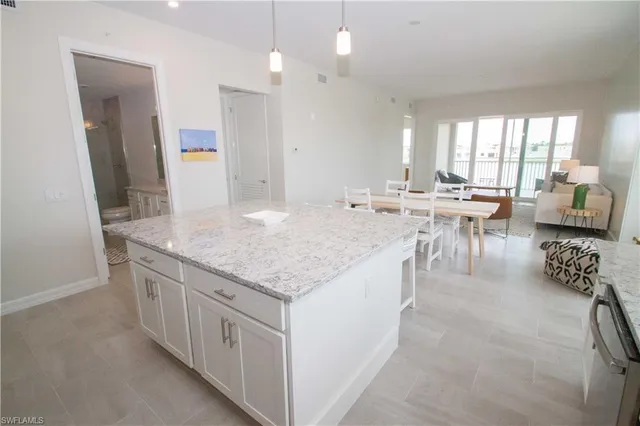 an open kitchen with granite countertop a sink and white cabinets