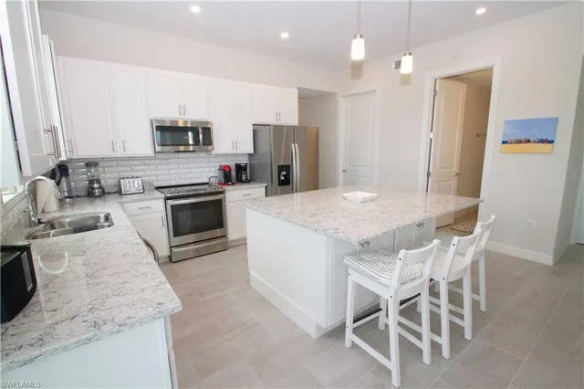 a kitchen with stainless steel appliances granite countertop a kitchen island hardwood floor sink stove dining table and chairs