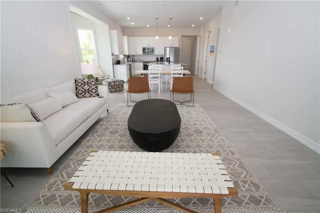 a living room with furniture a wooden floor and a kitchen view