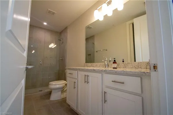 a bathroom with a granite countertop sink a toilet and a mirror