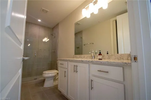 a bathroom with a granite countertop sink a toilet and a mirror