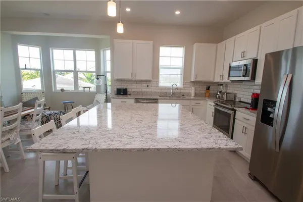 a kitchen with stainless steel appliances granite countertop a sink stove refrigerator and window
