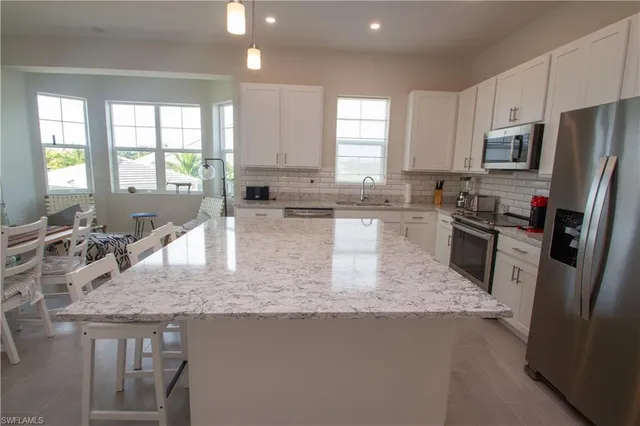 a kitchen with stainless steel appliances granite countertop a sink stove refrigerator and window