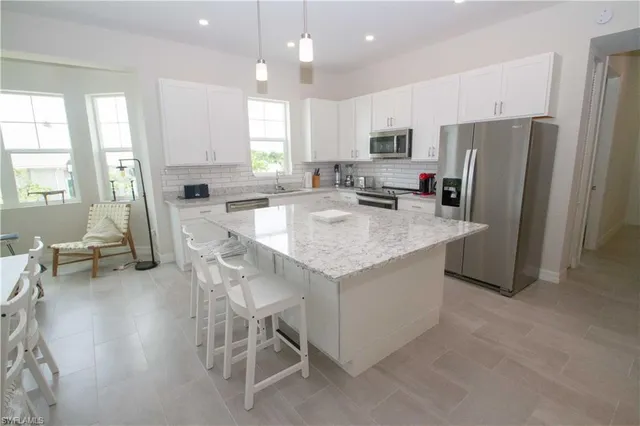 a kitchen with stainless steel appliances granite countertop a table chairs sink refrigerator and microwave