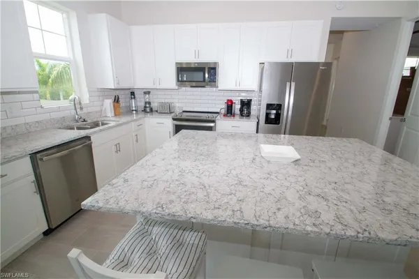 a kitchen with stainless steel appliances a refrigerator sink and microwave