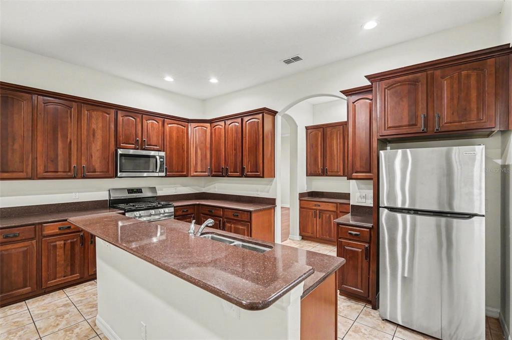 4819 Indian Deer Road Windermere, FL 34786 - Photo 9 of 30 a kitchen with granite countertop wooden cabinets a stove top oven a sink and dishwasher